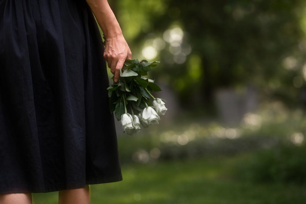 ilustrasi perempuan membawa bunga mawar putih ke kuburan (Freepik)