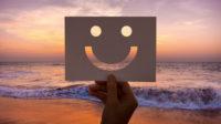 ilustrasi kertas dibentuk emoji senyum dengan pemandangan pantai (Freepik)