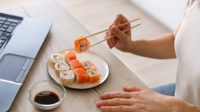 ilustrasi perempuan menyumpit makanan sushi (freepik)